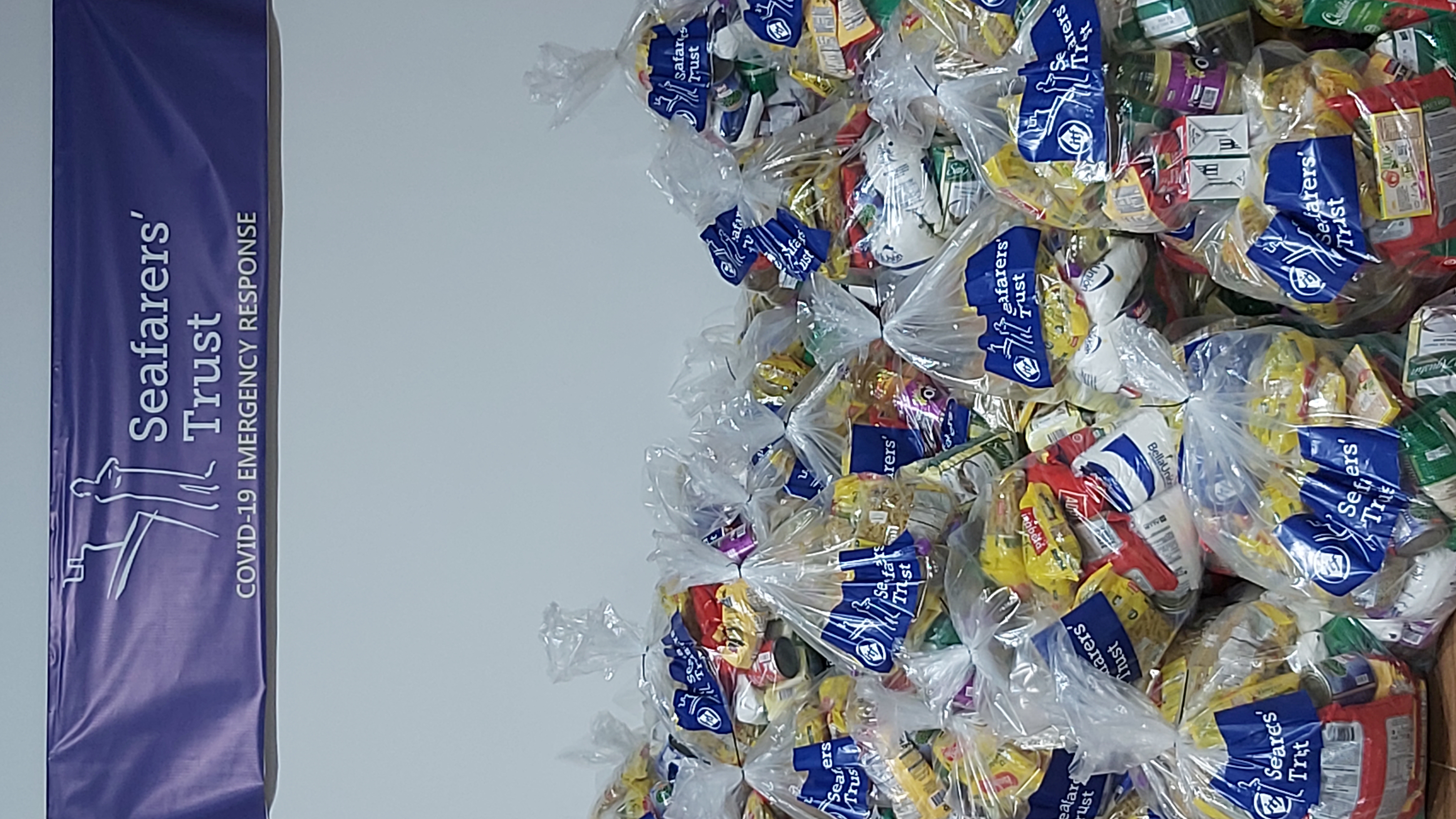 Imagen de una pila de paquetes de alimentos y suministros de higiene esenciales en bolsas transparentes