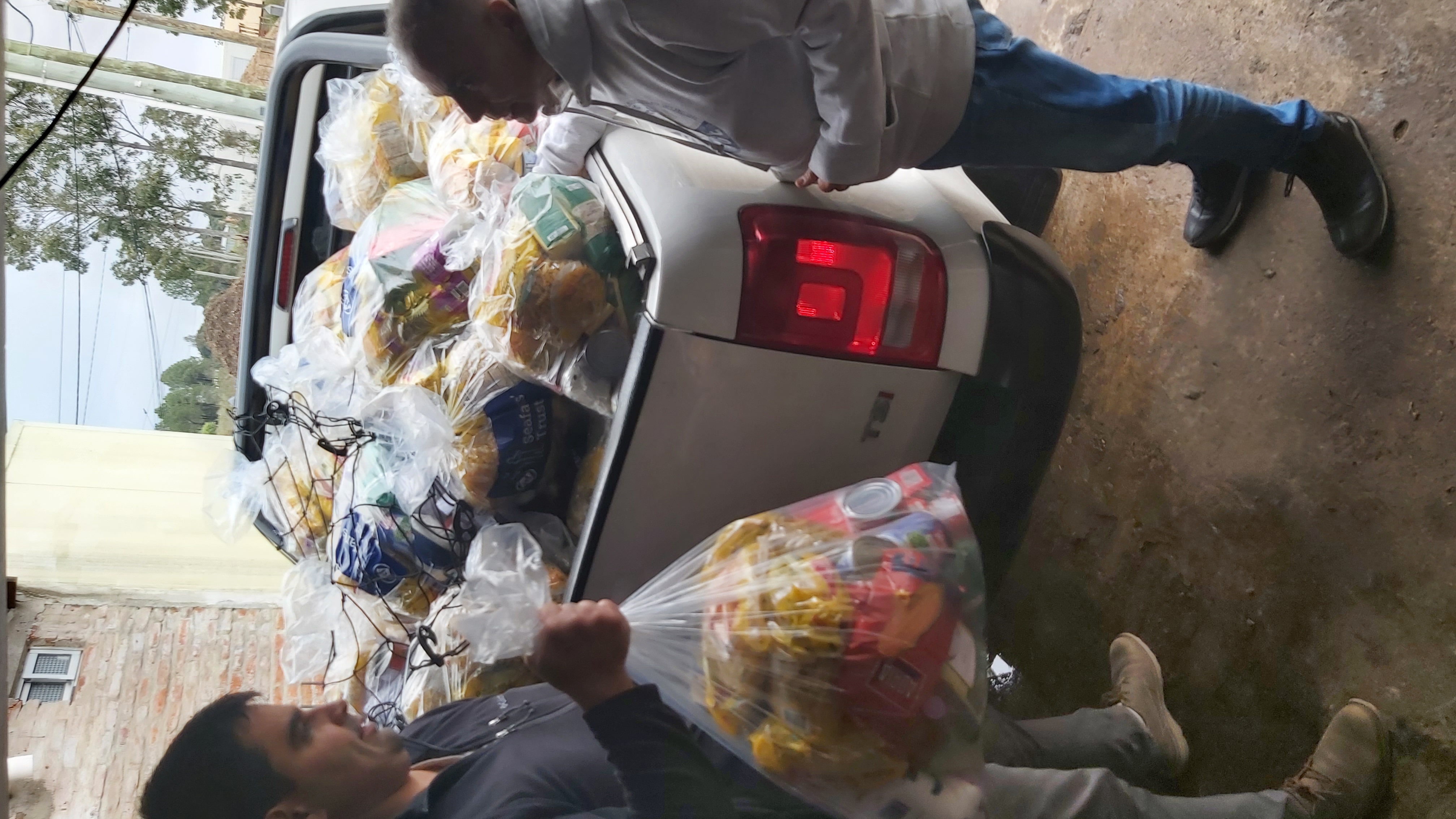 Imagen de paquetes de suministros de higiene y alimentos esenciales en la parte trasera de un camión listos para la entrega