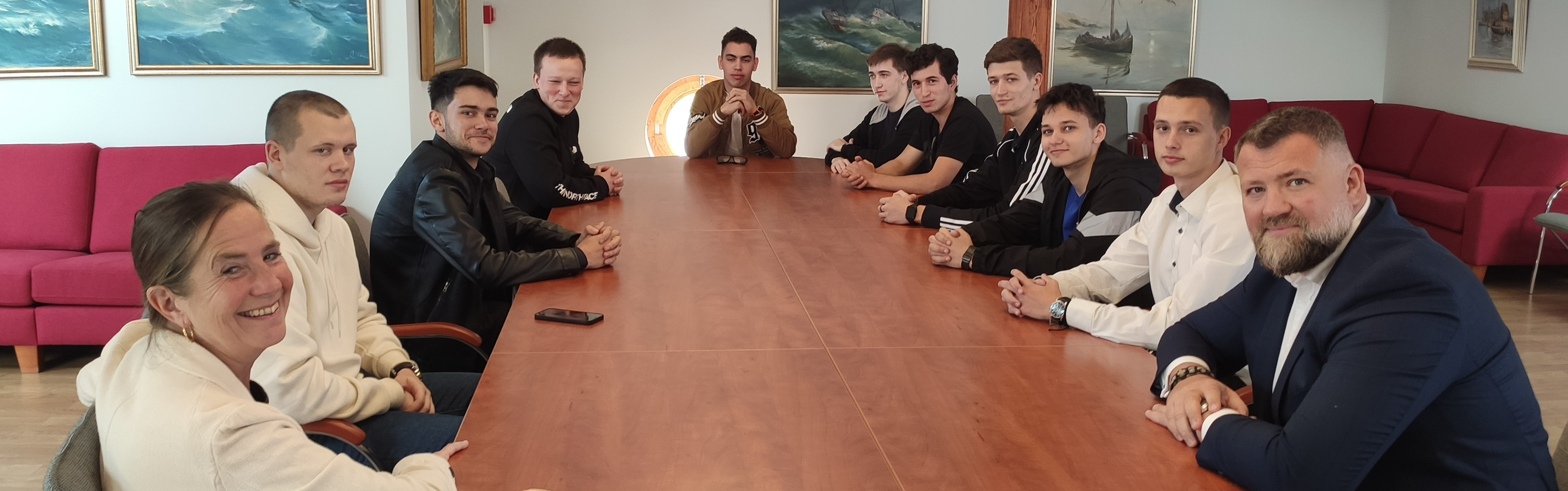 Ukrainian seafarer cadets, Katie Higginbottom (ITFST) and Oleg Grygoriuk (MTWTU) sit around a board table smiling at the camera.