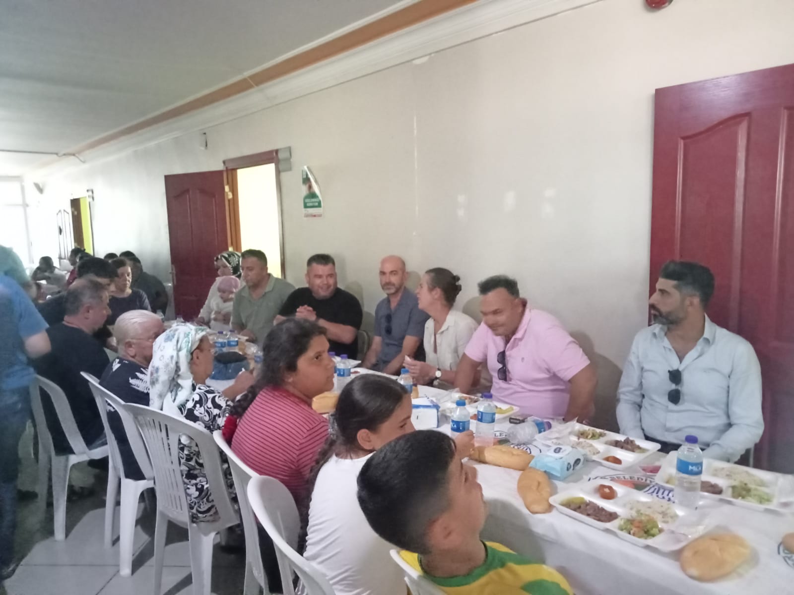 Several people made homeless by the earthquake sitting together at a long table to eat a meal