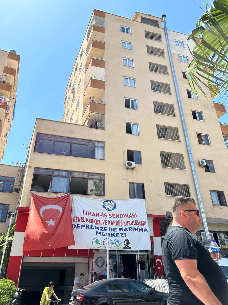 The front of the guesthouse in Mersin, a tall white multistorey building with a large canvas printed sign hung over the doorway