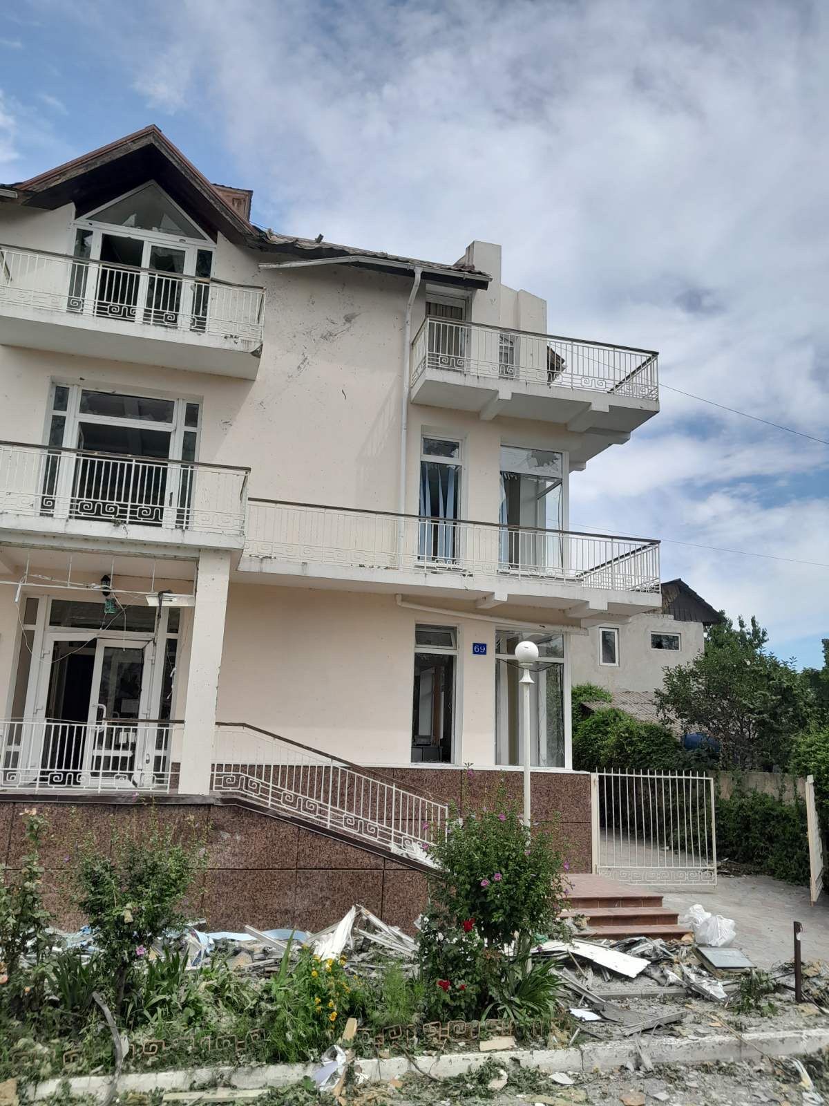 A picture of the front of Izmail Seafarers Centre. All of the windows have been smashed and there is glass and debris laying in the street in front of the buidling.