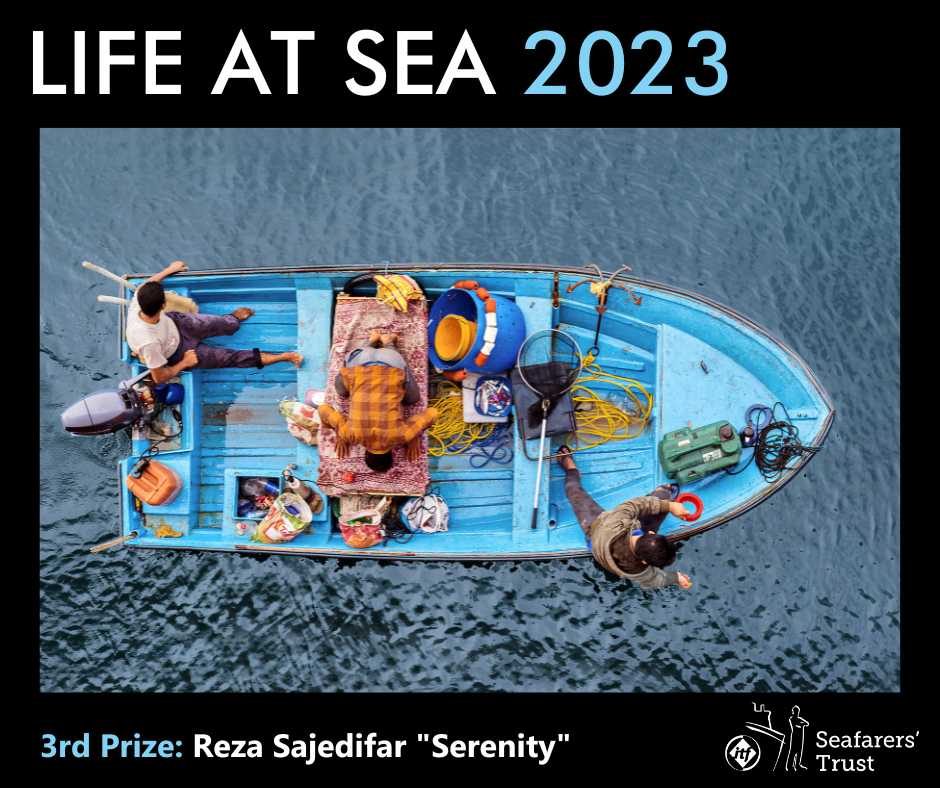 A graphic showing the 3rd Prize photo on a black background with text reading Life At Sea 2023 3rd Prize Reza Sajedifar "Serenity". The image shows a view downwards over the side of a ship to where a small fishing boat floats. In the boat a man is knelt at prayer on a prayer mat while his colleagues continue to fish.