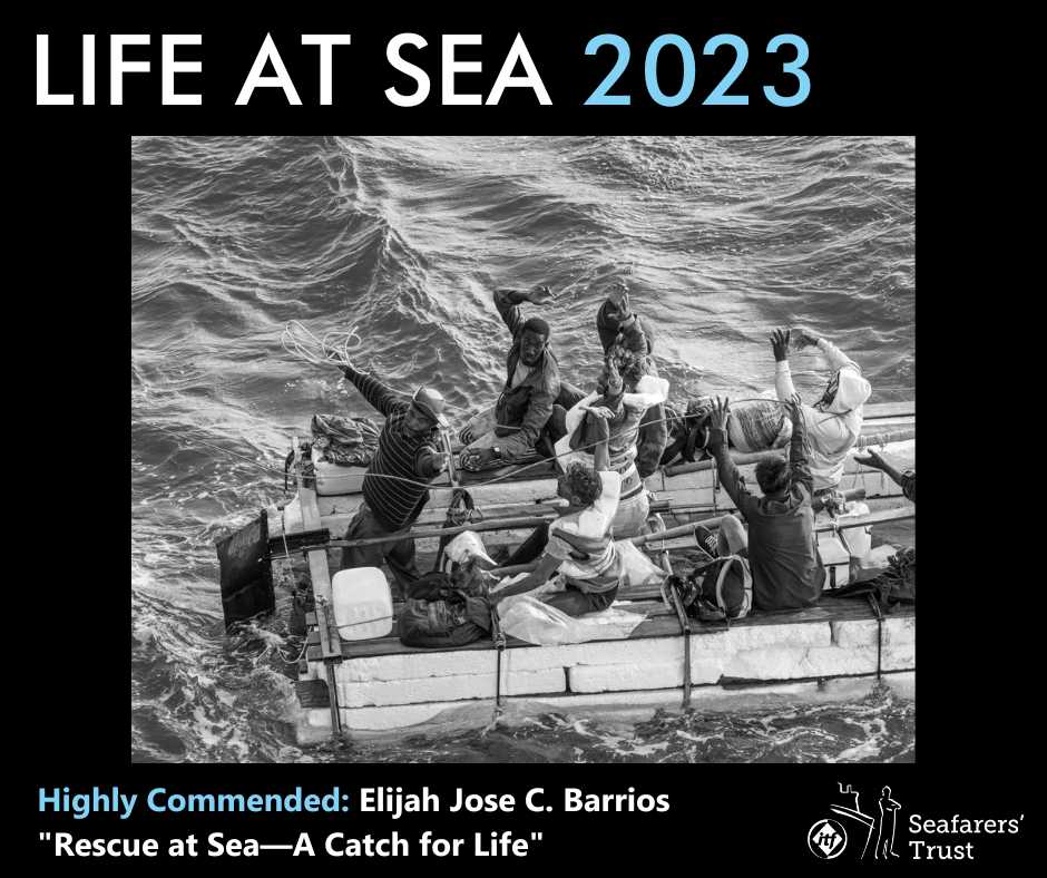 A graphic showing a Highly Commended Prize photo on a black background with text reading Life At Sea 2023 Highly Commended Elijah Jose C. Barrios "Rescue At Sea - A Catch For Life". The monochrome photo shows six men and a dog on a makeshift dinghy at sea. The boat appears to be made of polystyrene blocks, wooden planks and rope. Water can be seen in the bottom of the boat. The men are clearly in some distress and are waving and catching ropes thrown towards them.